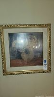 Full view of the framed floral print showing the ornate gold frame, beige mat, and floral bouquet in vase artwork.