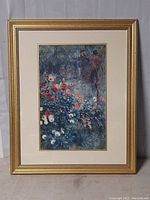 Front-facing photo of framed print showing garden and figures with colorful flowers and gold frame.