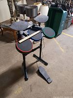 Electronic Guitar Hero drum set with three colored pads, two cymbal pads, foot pedal, and drumsticks on stand