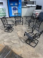 Five Hampton Bay patio chairs arranged outdoors on concrete, including two rocking swivel chairs and three stationary chairs, all painted black aluminum.