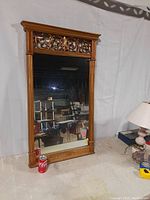 Full view of the large ornamental wall mirror showing carved wooden frame and clear glass.