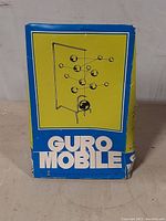 Factory packaging of the Guro Mobile kinetic sculpture with visible box damage shown on blue and yellow box