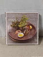 Box front showing the Mikasa vintage look Lazy Susan with food items displayed on the wooden surface.