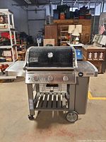 Front view of grill with lid closed showing control panel, knobs and open cart base.