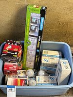 Full lot view showing various boxed and loose lightbulbs, including 60W compact fluorescents and boxed incandescent bulbs.