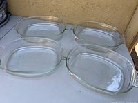 Four matching Pyrex glass casseroles arranged on a table, showing shape and size.