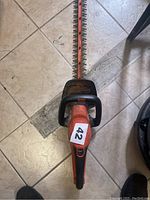 Top view of the Black & Decker orange and black electric hedge trimmer showing long blade with dual cutting edges and front handle with protective guard.