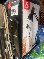 Box of Globe brand black desk lamp with adjustable arm shown on front and side with lamp in use on desk