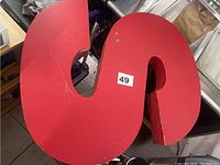 Top view of large red letter 'S' showing scratches and wear.