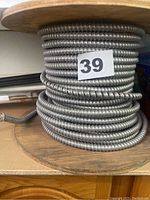 Large roll of silver flexible metal conduit wiring on a wooden spool with label number 39.