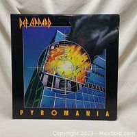 Front cover of Def Leppard Pyromania vinyl album showing explosion and building with crosshairs, slight crease on top center.