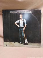 Front cover of Eric Clapton live album 'Just One Night' showing Eric Clapton standing with a guitar.