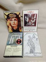 Four heavy metal cassette tapes including King Diamond, Judas Priest, Kick Axe, and Metallica. Clear plastic cases with front cover artwork.