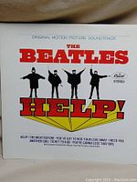 Front album cover of The Beatles 'Help!' soundtrack showing the band members in an iconic pose with the album title in bold red and yellow.
