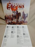 Front cover of Saxon's Crusader vinyl album showing the medieval battle scene artwork and lyric sheet with song lyrics.