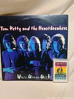 Front cover of the vinyl album 'You're Gonna Get It!' by Tom Petty and the Heartbreakers showing band members in blue and purple tones and the album title.