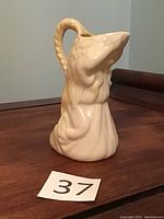 Side view of Belleek Undine cream pitcher showing sculptural handle and draped detail