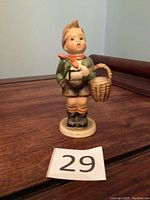Front view of the Hummel figurine showing the boy holding a basket wearing traditional attire.