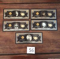 Five customized USA $2 notes laid out on a wooden surface, each featuring a different Pawn Stars cast member in a black and gold design with 24KT gold leaf accents.