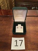 Pair of amethyst stud earrings displayed in a dark green velvet box with cream satin interior.