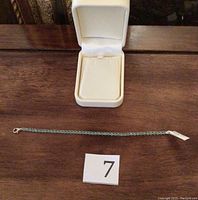 Bracelet laid out with white jewelry box and number card 7