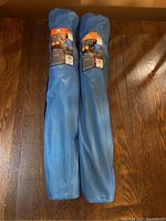 Two blue carrying sleeves with camping chairs inside, showing exterior wear from storage.