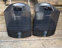 Two black Aro-Swiss humidifiers side by side on wooden surface, showing front control dials and water tanks.