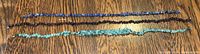 Three natural stone necklaces laid out flat on wooden surface showing length and stone detail