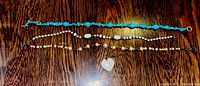 Photo shows three necklaces laid flat on a wooden surface: a blue stone necklace, a white stone necklace, and a pearl necklace. Also visible is a heart-shaped pendant with a white stone.