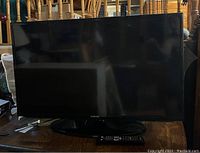 Front view of Samsung 40 inch smart TV showing black screen and base stand on wooden surface.