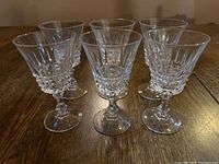 Six clear crystal liquor glasses with textured cut design, shown upright on wooden surface