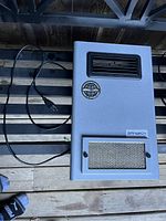 Front view of gray Sanuvox air purifier on a pallet showing power cord and vent openings.