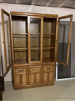 Front view of china hutch with two glass doors open showing shelves inside.