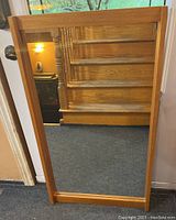 Full frontal view of the rectangular wall mirror reflecting a wooden staircase and interior space, showing the teak frame and glass surface clearly.