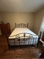 Full view of queen size metal bed frame with mattress on wood floor
