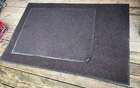Two dark brown rugs on a wood deck surface, showing size and condition including curled edge.
