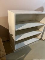 Front and side view of white wooden shelving unit showing three shelves and overall dimensions.