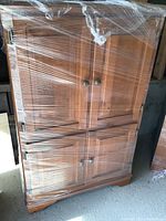 Front view of the cabinet showing four paneled doors with metal knobs and decorative molding.