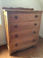 Front view of four-drawer pine dresser with turned knobs and scalloped backsplash