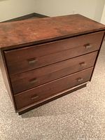 Front view of wooden dresser showing four drawers with metal handles and surface wear.