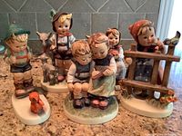 Group shot of six Goebel West German porcelain figurines featuring children and small animals on a kitchen counter.