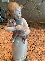 Porcelain figurine of a girl in a long dress holding a lamb, made by Lladro.
