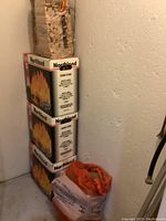 Stack of three Northland firewood starter boxes with one bag of kindling wood on top and another bag nearby.