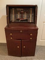 Full view of wooden cabinet with roll-top door and drawers.