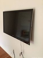 50-inch Toshiba TV wall mounted against wall, cables visible hanging down