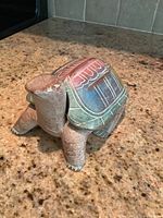 Front view of carved turtle figurine with detailed shell pattern and textured legs and head.
