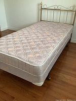 Full view of twin bed set including brass headboard, mattress, box spring, and bed frame.