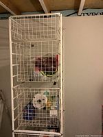 Full view of tall white metal wire basket rack with contents including paper towel roll and packaged goods