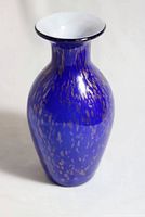 Full view of cobalt blue glass vase with gold speckles and white inside rim on neutral background.