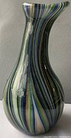 Close-up of the vase showing its curvilinear shape with multicolored vertical swirls including blue, green, and black.